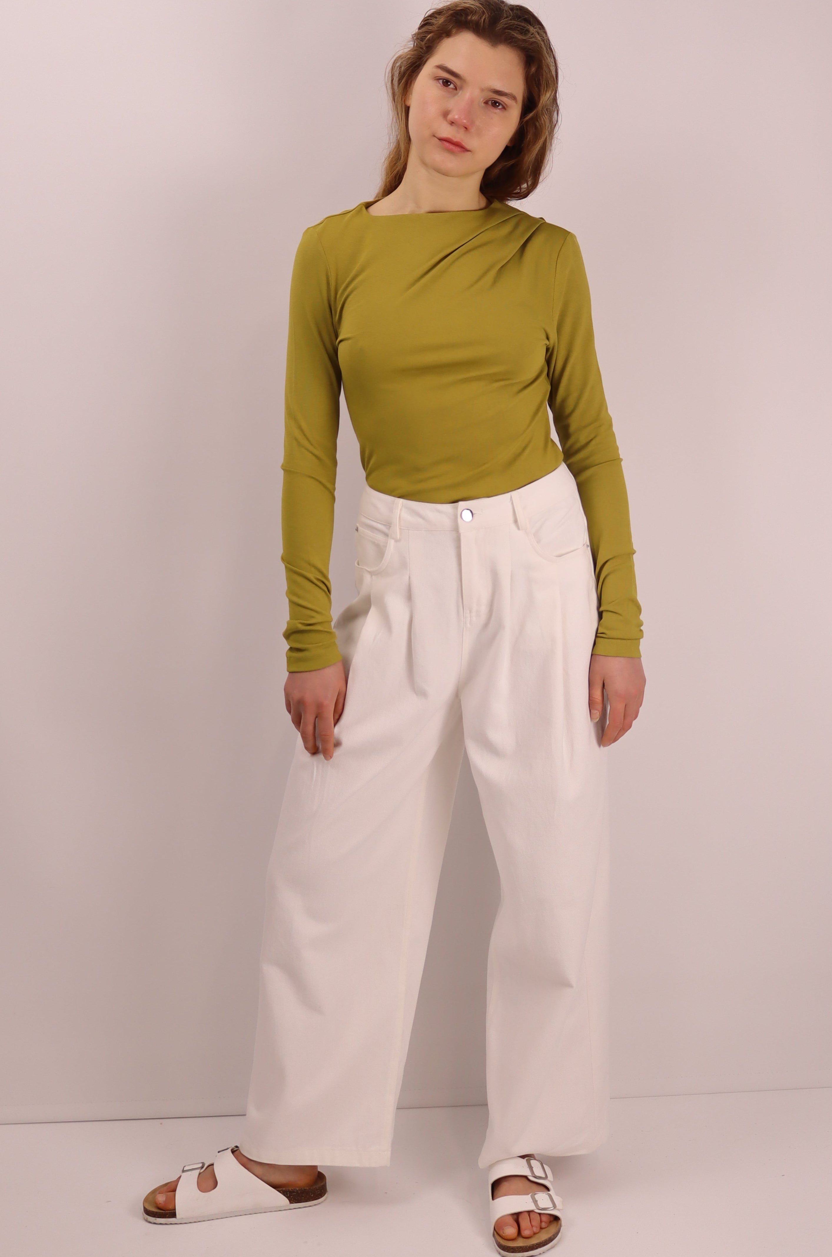 Person wearing a green top and white pants.