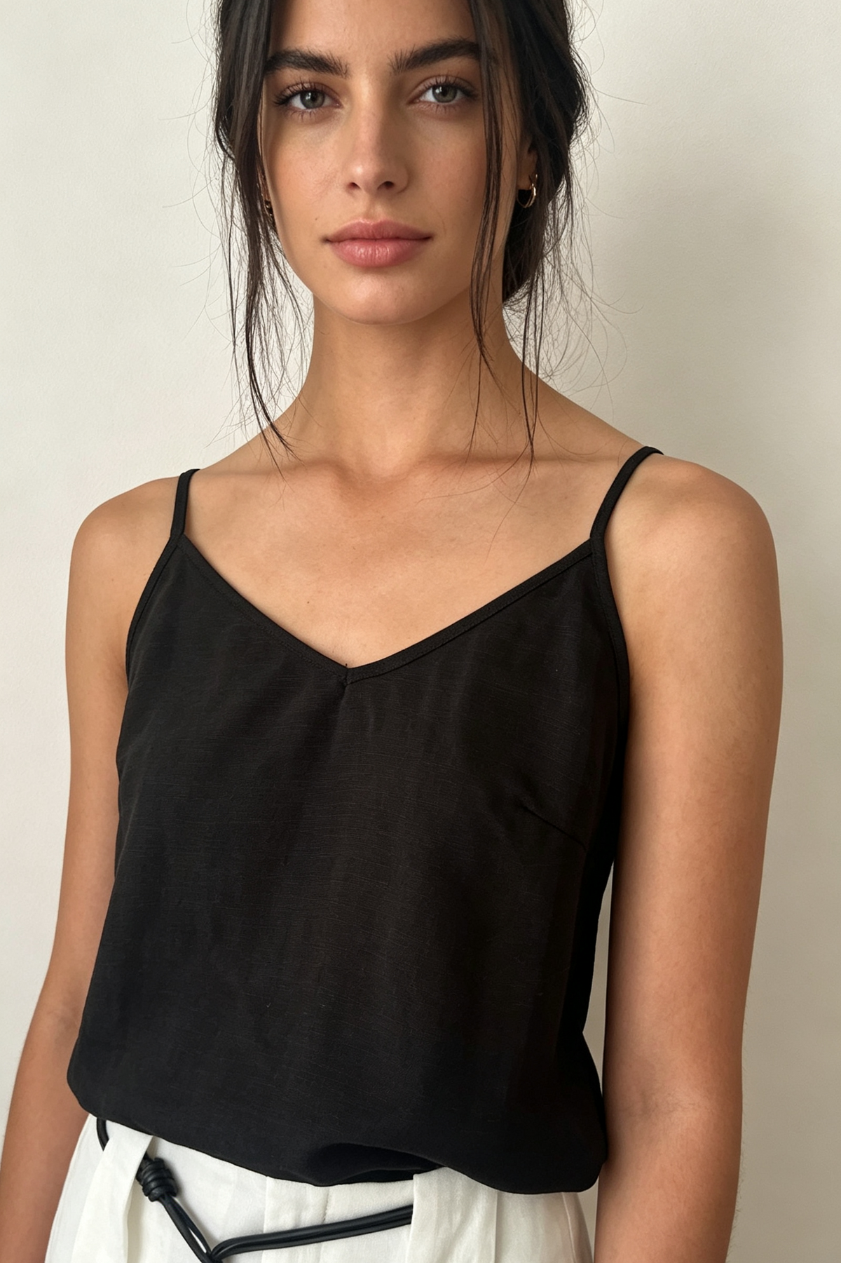 Model wearing a black linen blend V-neck camisole with fine shoulder straps, styled with floral print wide leg pants.
