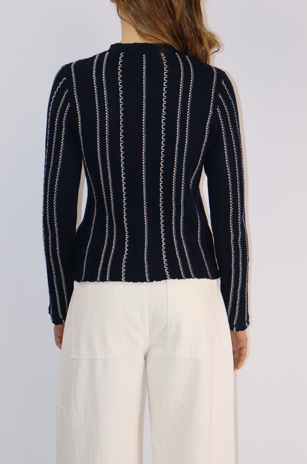 Person wearing a black and white striped sweater over a white shirt on a light gray background