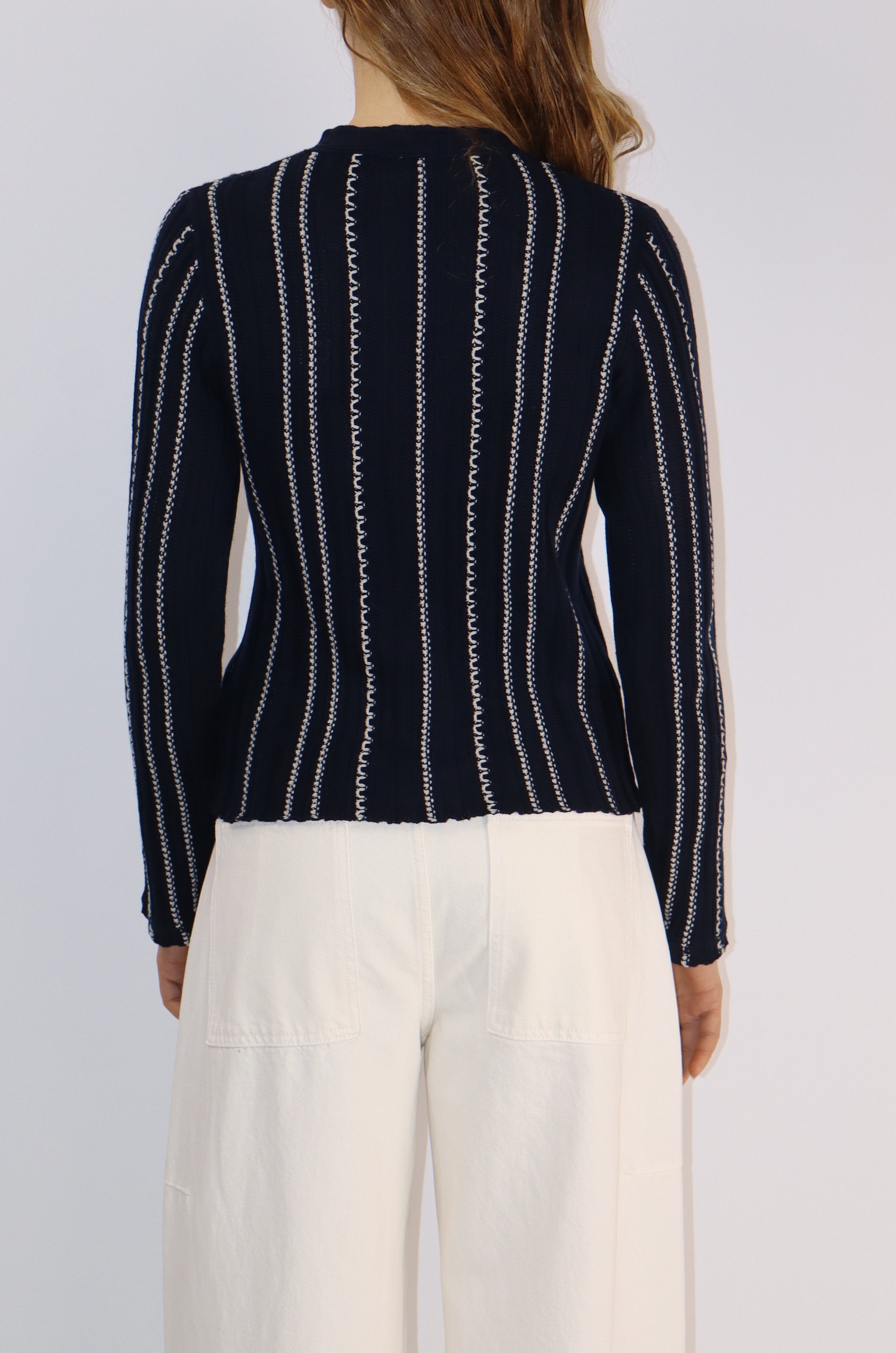 Person wearing a black and white striped sweater over a white shirt on a light gray background