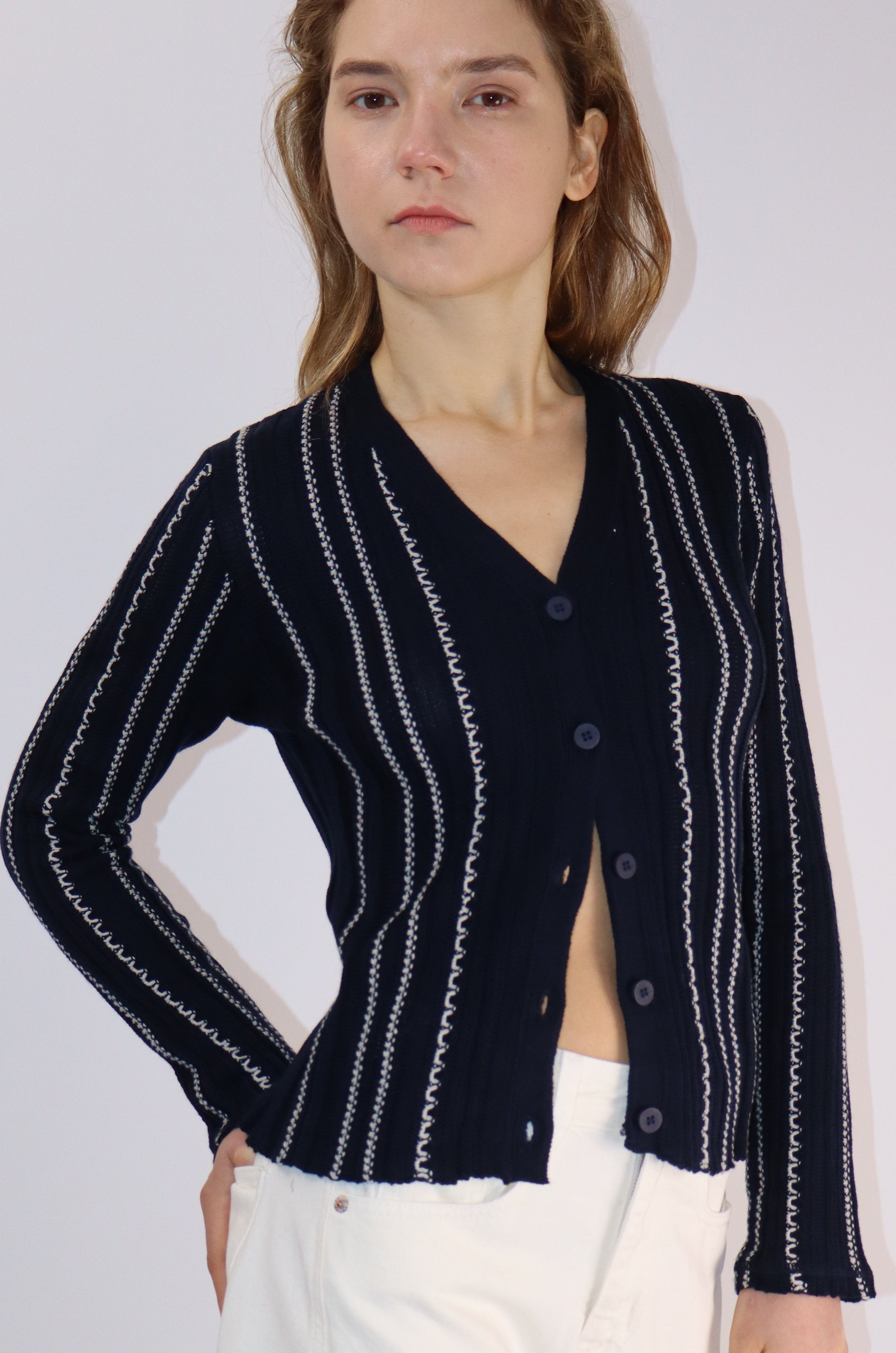 Person wearing a navy blue cardigan with white patterns on a light gray background