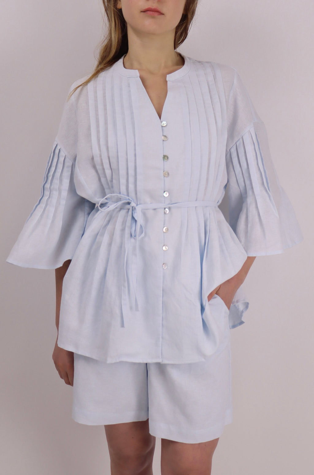 Woman wearing a light blue striped outfit against a plain background
