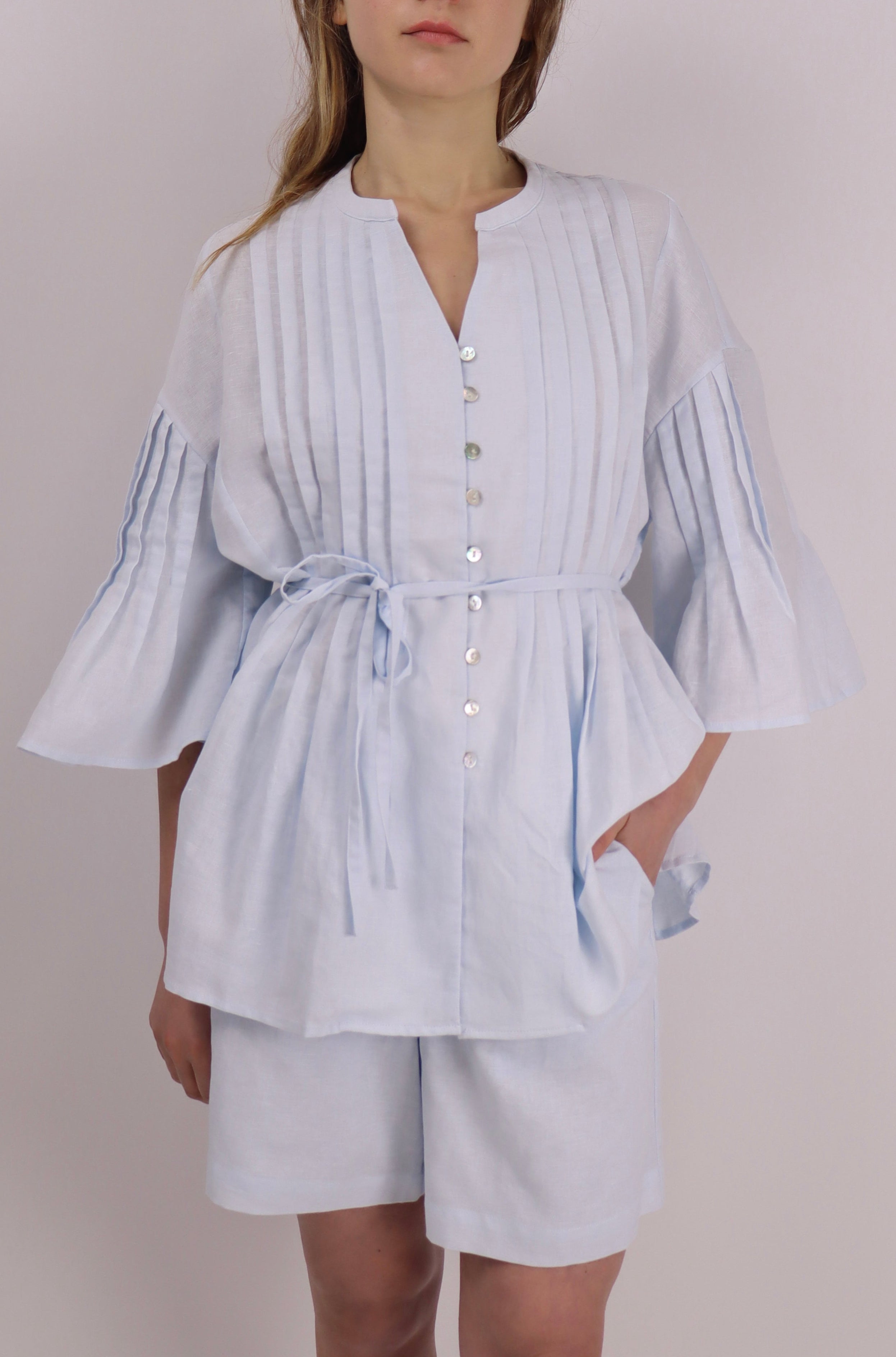 Woman wearing a light blue striped outfit against a plain background