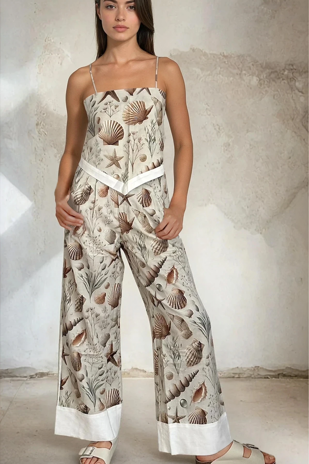 Woman wearing a seashell print jumpsuit with a white background