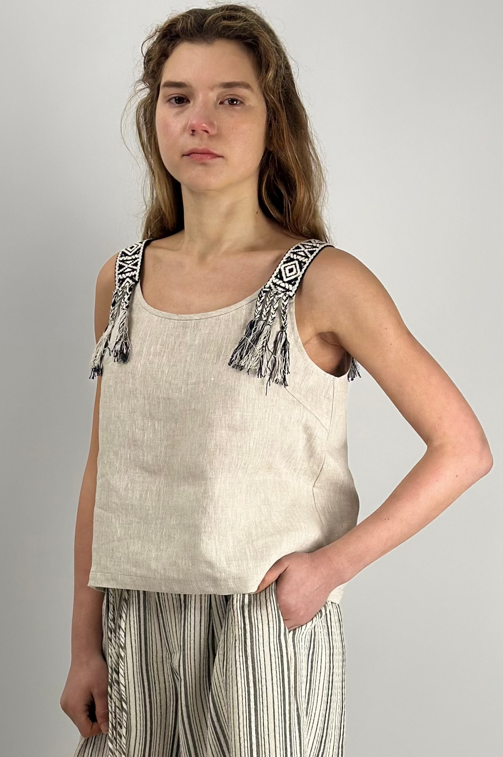 Woman wearing Seaside Breeze Top made of 100% linen, relaxed fit with refined neckline and subtle shoulder detail, styled for everyday wear
