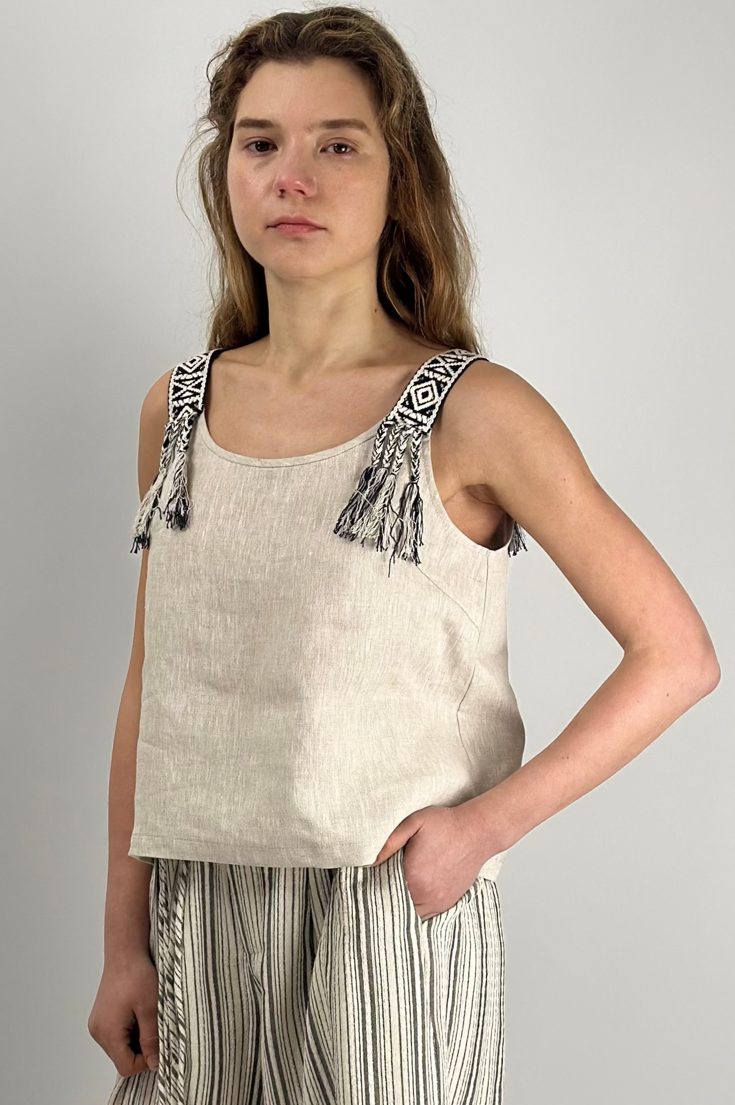 Woman wearing Seaside Breeze Top made of 100% linen, relaxed fit with refined neckline and subtle shoulder detail, styled for everyday wear