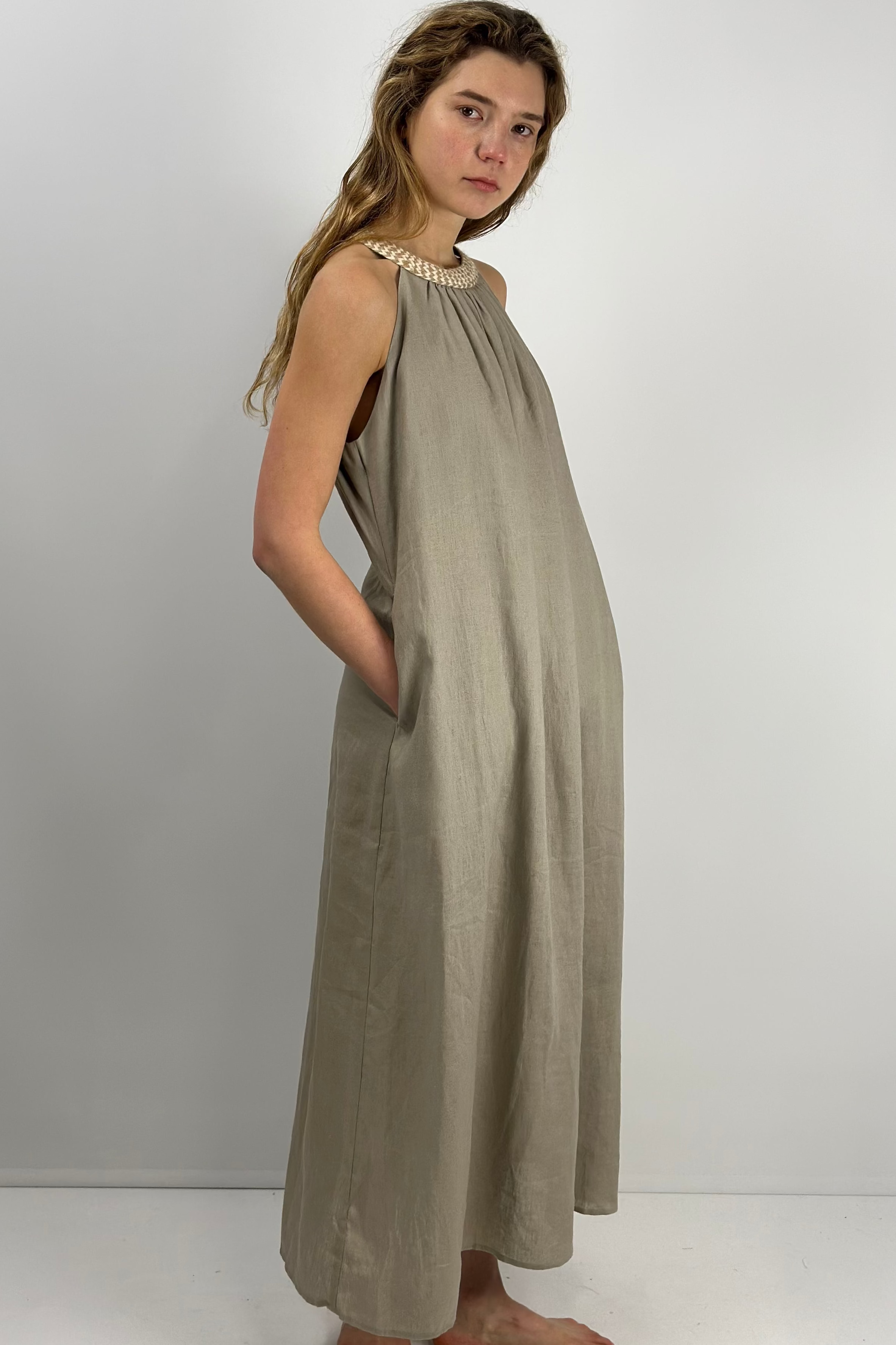 Woman wearing a  khaki lien maxi dress against a white background