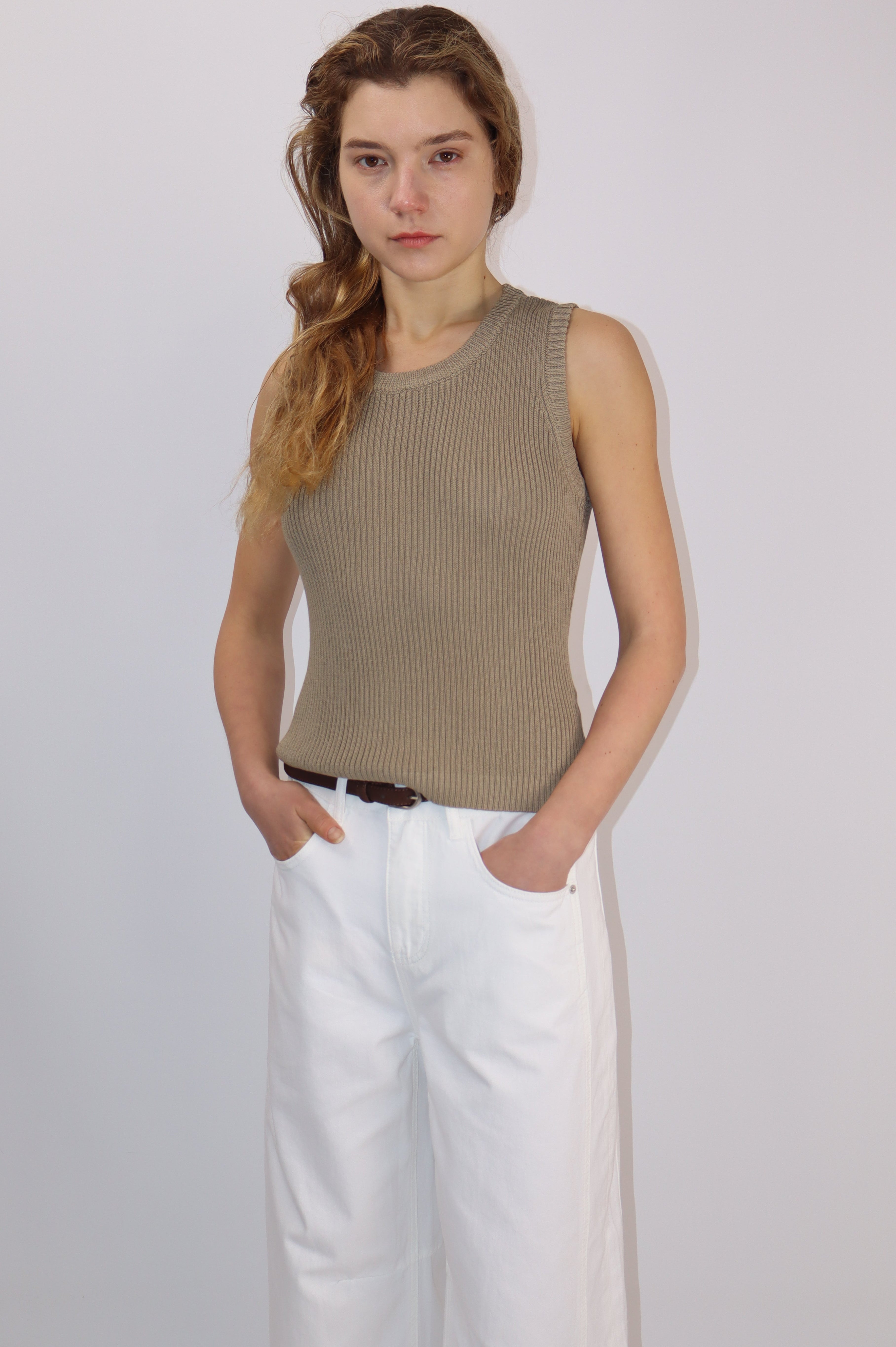 Model wearing a sleeveless knit top with textured back panel, styled with wide-leg white pants.