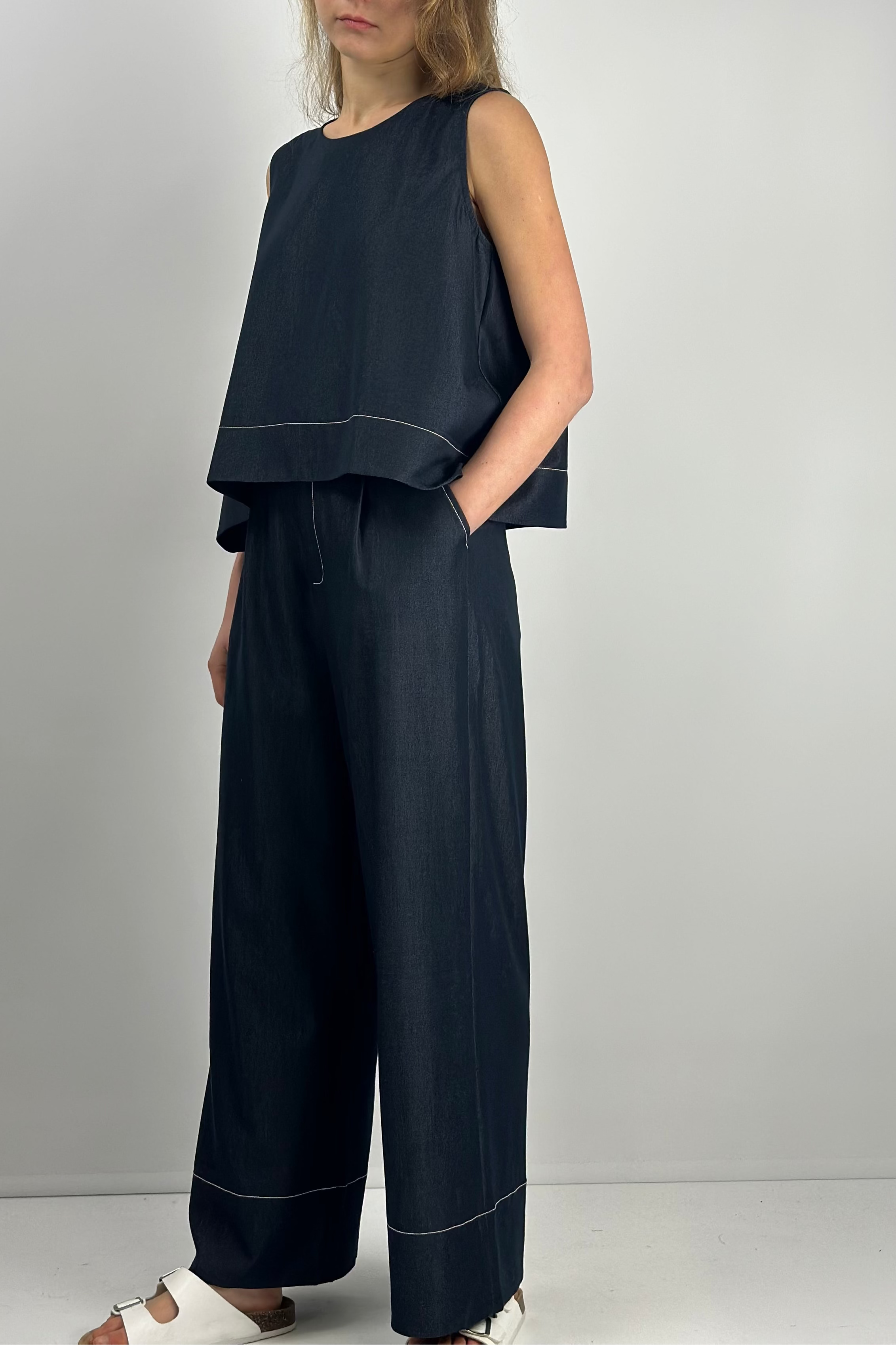 Woman wearing a dark blue sleeveless top and wide-leg pants 