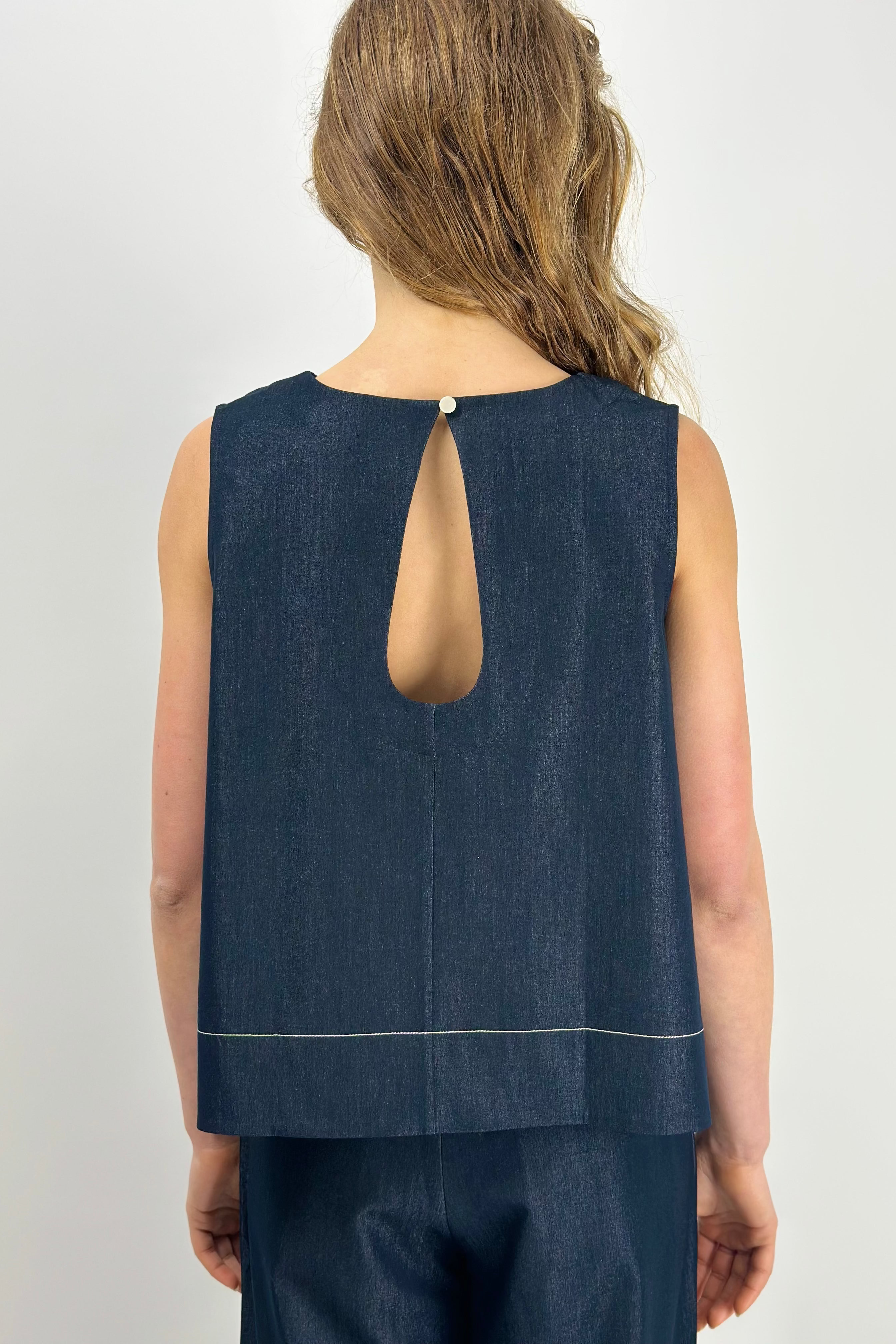Person wearing a navy sleeveless top with an cut out back on a white background