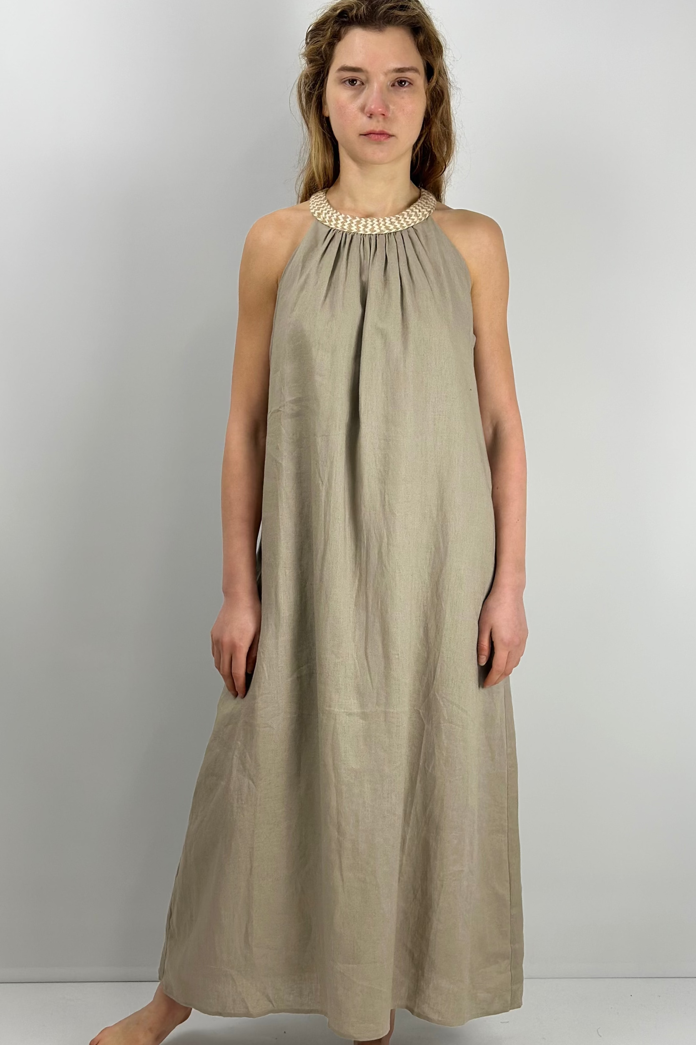 Woman wearing a long linen dress against a white background